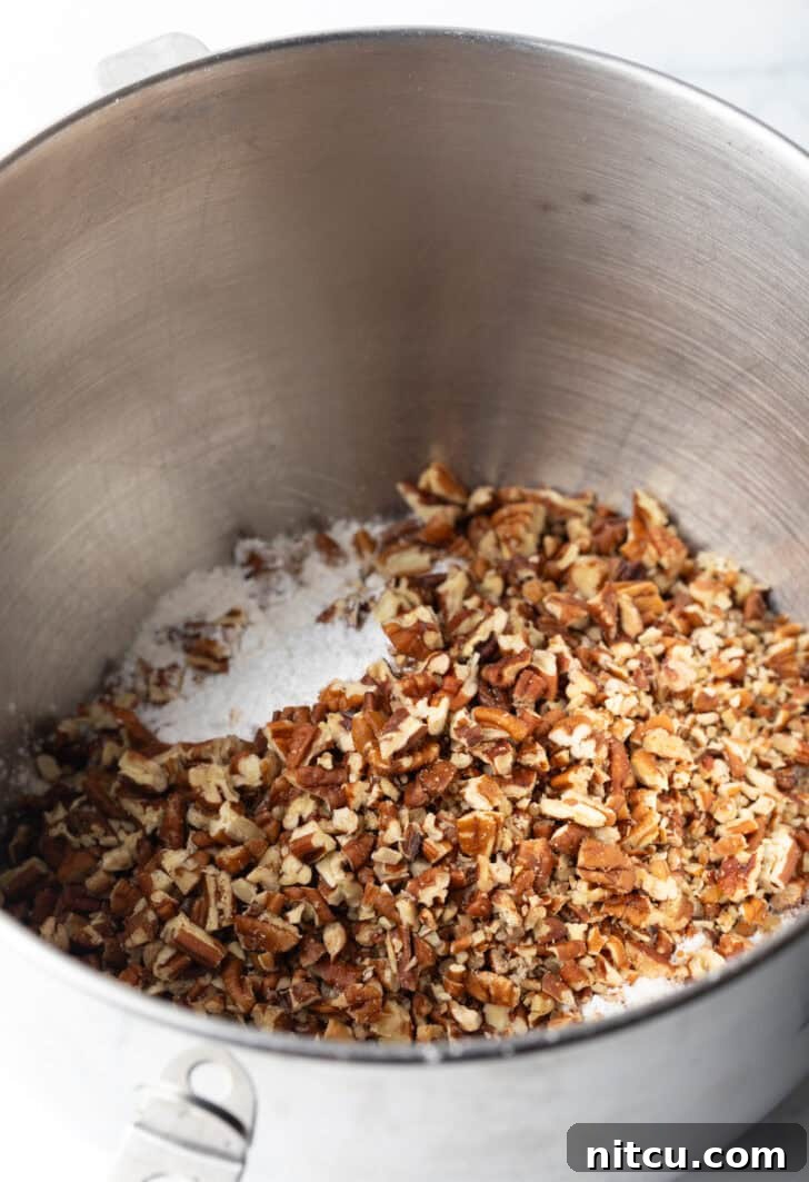 Crushed nuts in the bottom of a metal mixing bowl.