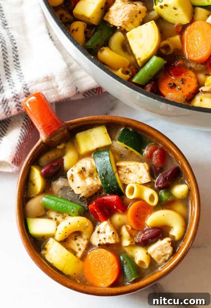 A close-up, top-down view of a generously filled large mug of chicken minestrone soup, steaming and ready to be savored.
