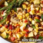White pot brimming with chicken minestrone soup and springs of fresh rosemary.