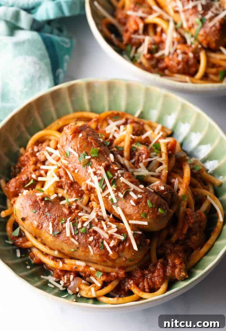 Slow-Simmered Sunday Meat Sauce 2 Green bowl with Sunday gravy pasta with meat sauce and sausages.