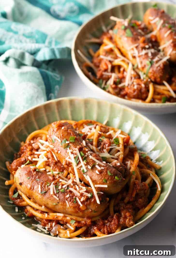 Slow-Simmered Sunday Meat Sauce 11 Green bowl with Sunday gravy pasta with meat sauce and sausages.