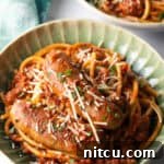 Slow-Simmered Sunday Meat Sauce 13 Green bowl with Sunday gravy pasta with meat sauce and sausages.