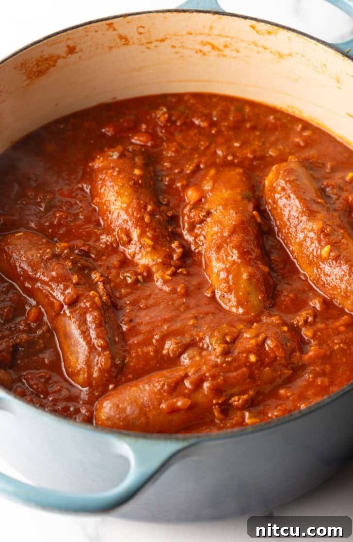 Slow-Simmered Sunday Meat Sauce 8 Large Italian sausages cooking in tomato sauce.