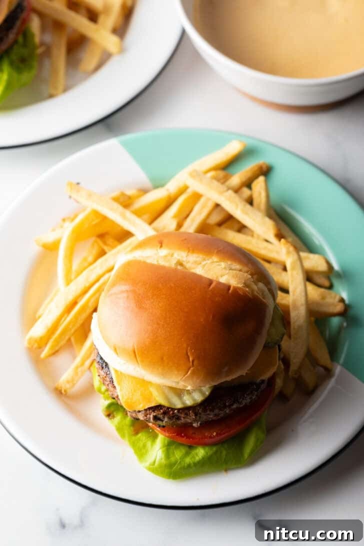 The Ultimate Homemade Burger Spice Blend 11 A perfectly cooked burger on a plate, surrounded by a pile of golden french fries, ready to be enjoyed.