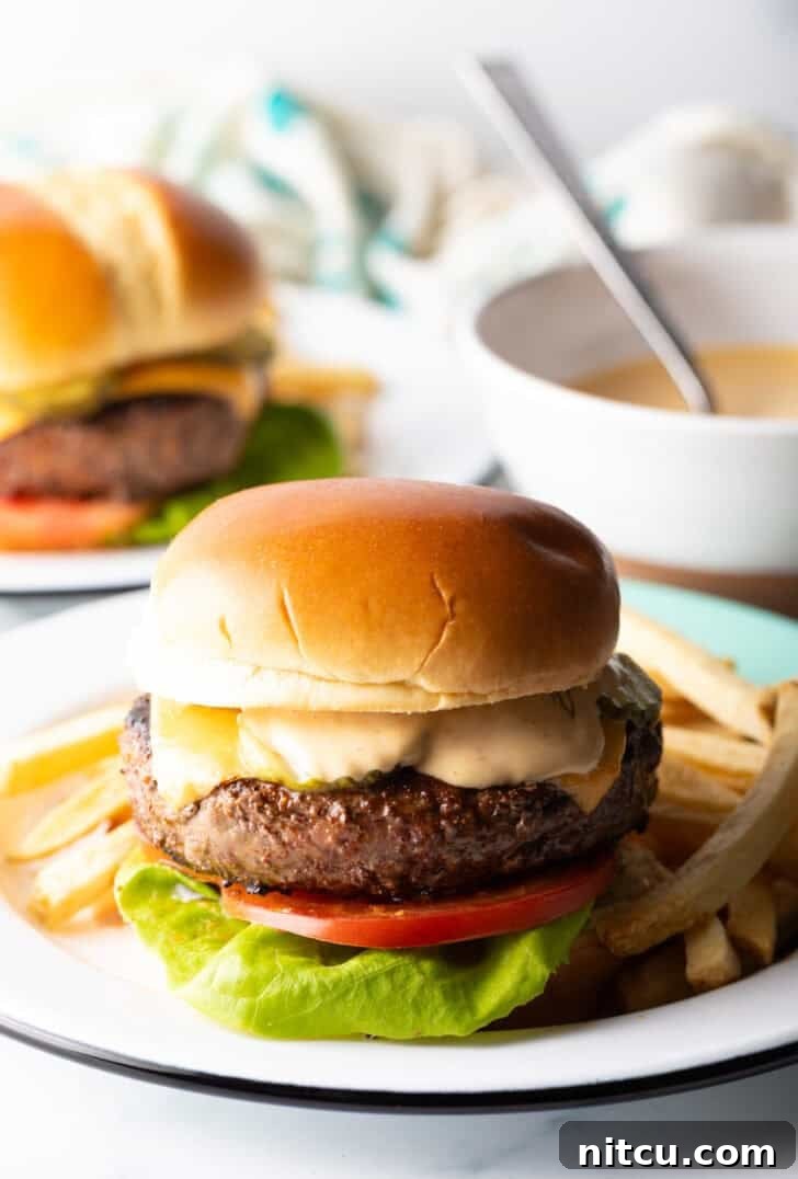 The Ultimate Homemade Burger Spice Blend 4 A mouth-watering cheeseburger, perfectly cooked and topped, served alongside a generous portion of golden-brown french fries on a white plate.