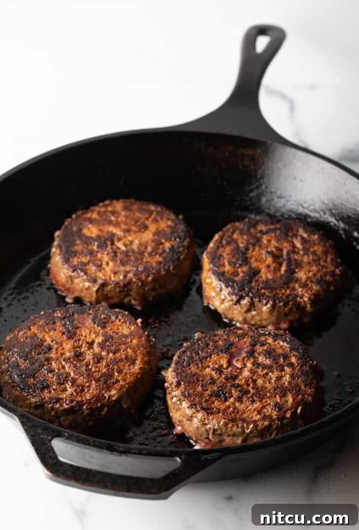 The Ultimate Homemade Burger Spice Blend 9 Four perfectly cooked hamburgers resting in a well-seasoned cast iron skillet, showcasing their delicious crust.