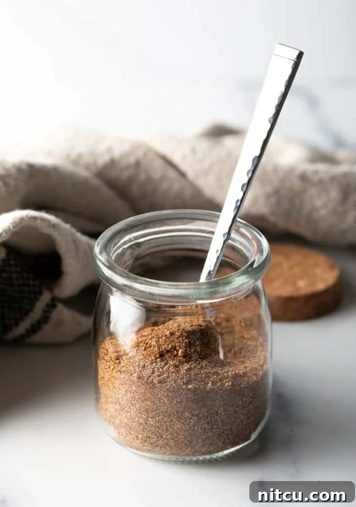 Signature Pork Chop Seasoning 2 Small glass jar with homemade pork chop seasoning and a metal spoon, ready for use.