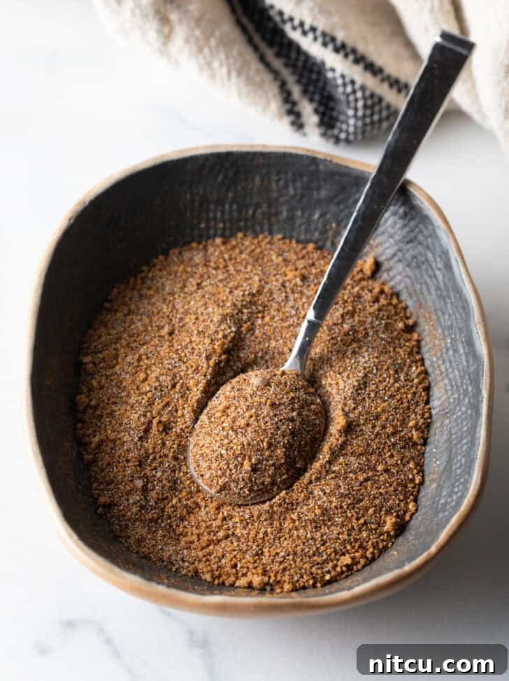 Signature Pork Chop Seasoning 8 Blend of spices being mixed in an oval dish with a metal spoon.