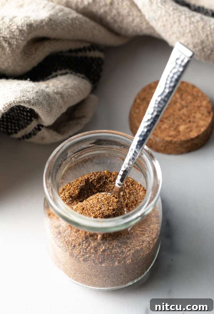 Signature Pork Chop Seasoning 9 Small glass jar with the finished pork chop seasoning and a metal spoon.