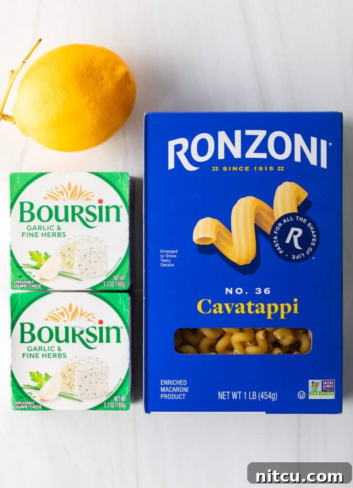 Decadent Boursin Pasta 5 Top-down view of ingredients for Boursin cheese pasta: a box of cavatappi, two boxes of Boursin cheese, and a whole lemon.