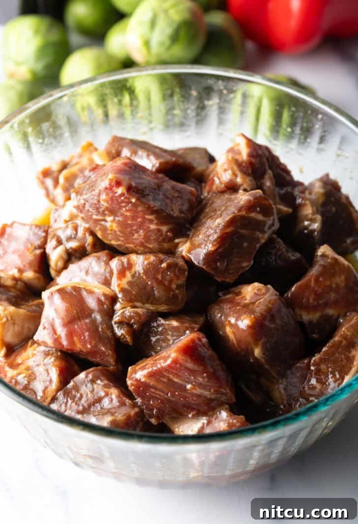 Chunks of steak thoroughly marinating in a glass bowl, absorbing all the rich flavors.