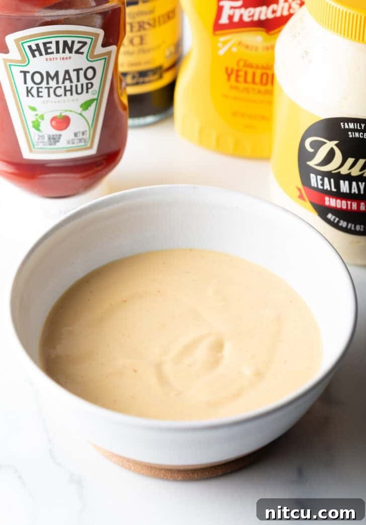 Signature Burger Dressing 7 A creamy, orange-hued homemade burger sauce is presented in a white bowl, perfectly blended and ready for use.