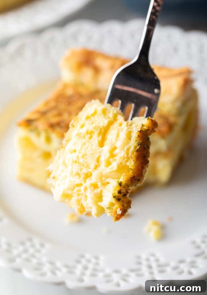 The Ultimate Effortless Breakfast Bake 13 A fork proudly holds up a perfect mouthful of fluffy, golden egg casserole, showcasing its tender texture.