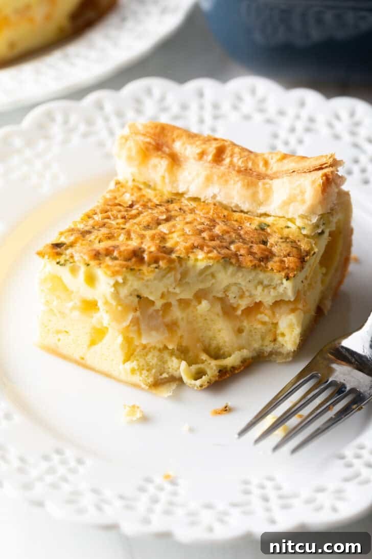 The Ultimate Effortless Breakfast Bake 4 A perfectly portioned square of fluffy egg casserole resting on a pristine white plate, accompanied by a fork.