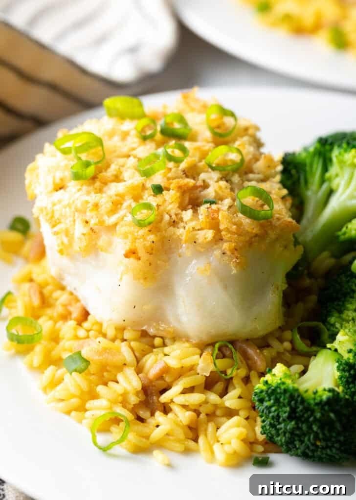 Crispy potato chip crusted sea bass served on a plate with vibrant yellow rice and tender cooked broccoli, ready for a delightful meal.