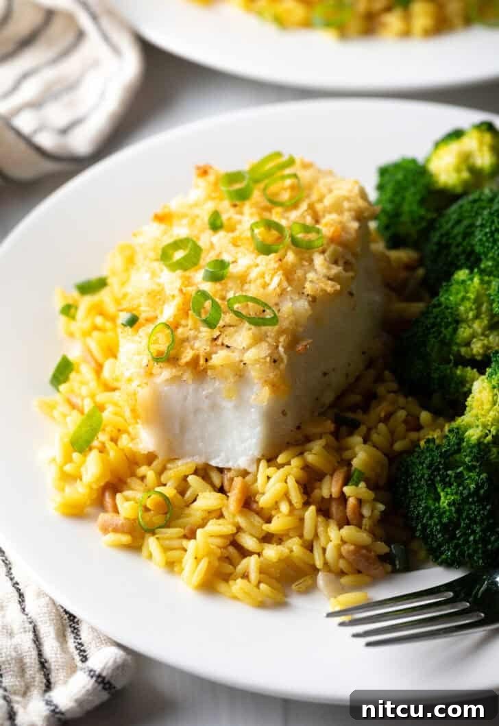 The full spread: perfectly baked potato chip crusted sea bass served with fluffy yellow rice and vibrant cooked broccoli, showcasing a balanced and delicious meal.