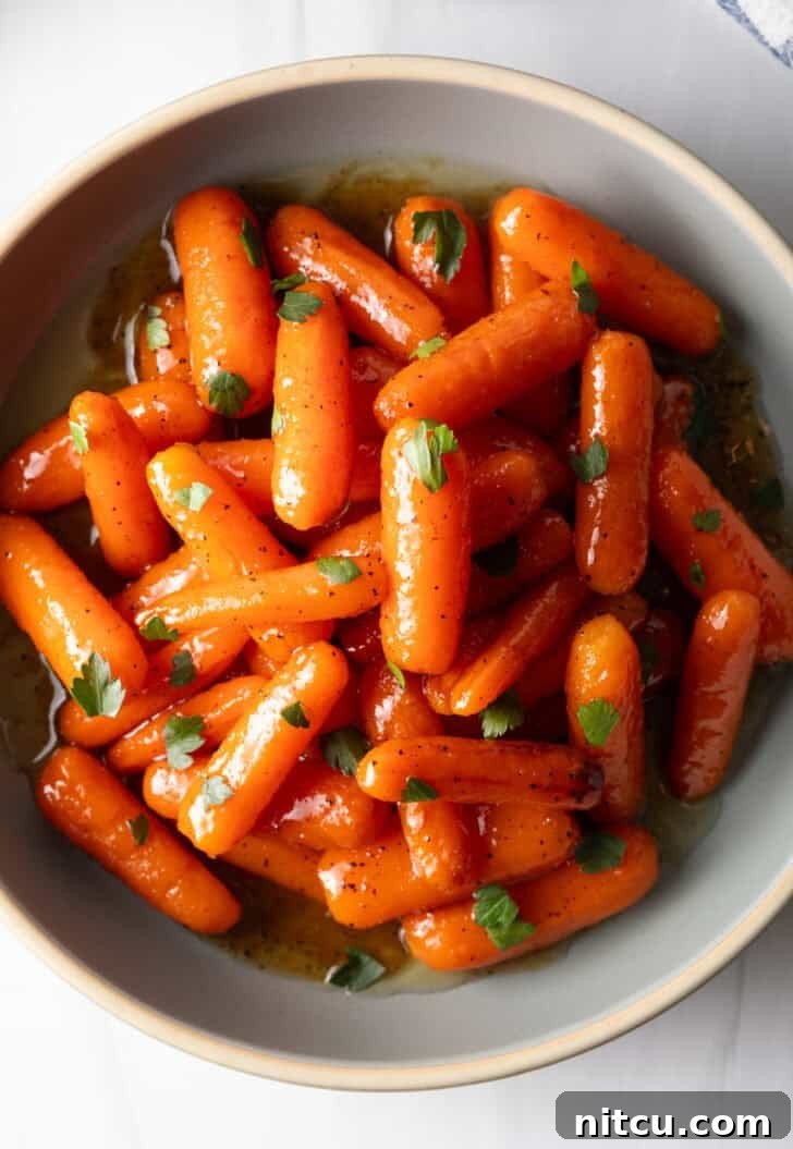 Top down bowl of glazed honey baby carrots sprinkled with chopped parsley.