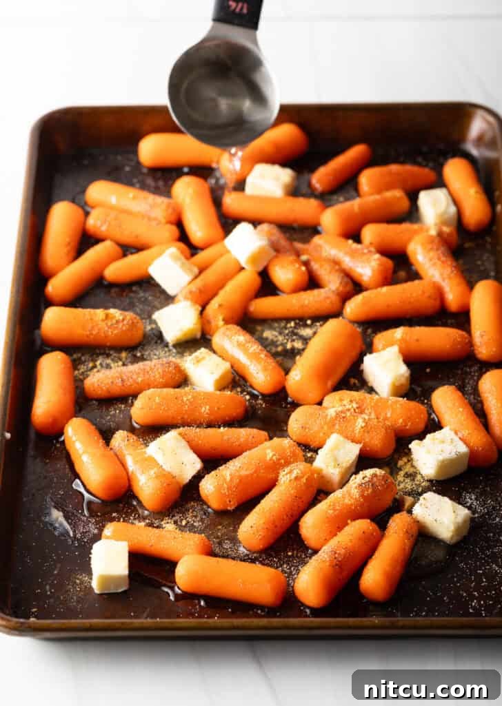 Baking sheet with baby carrots and cubes of butter.