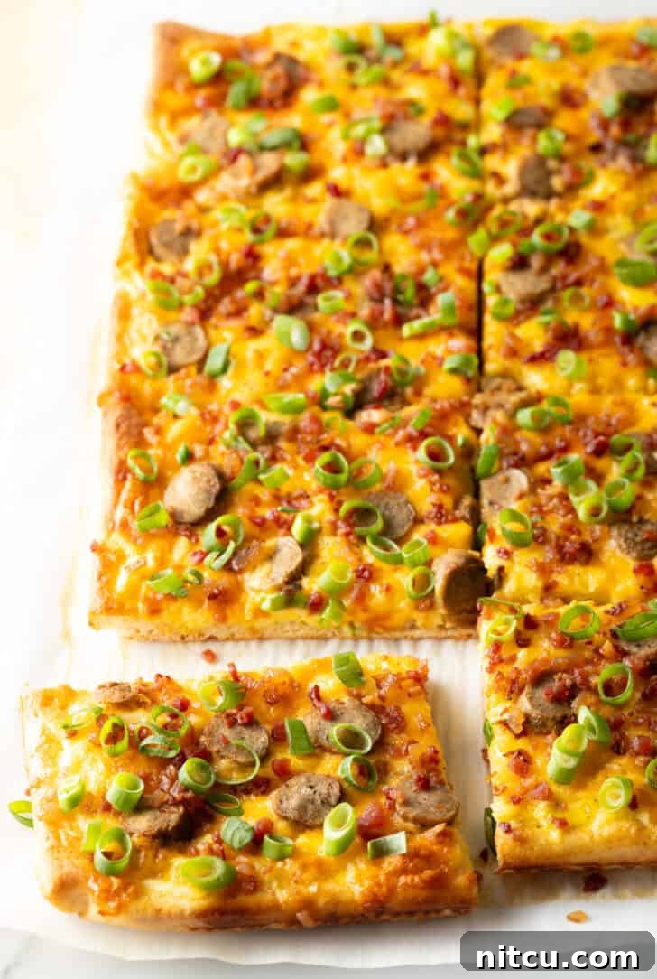 Daybreak Pizza 2 A rectangular baking sheet tray showcasing a vibrant breakfast pizza, generously loaded with melted cheese, sliced sausage, and fresh green onions. The pizza has been perfectly cut into 8 individual rectangular slices, with one piece gently pulled away, highlighting its inviting layers.