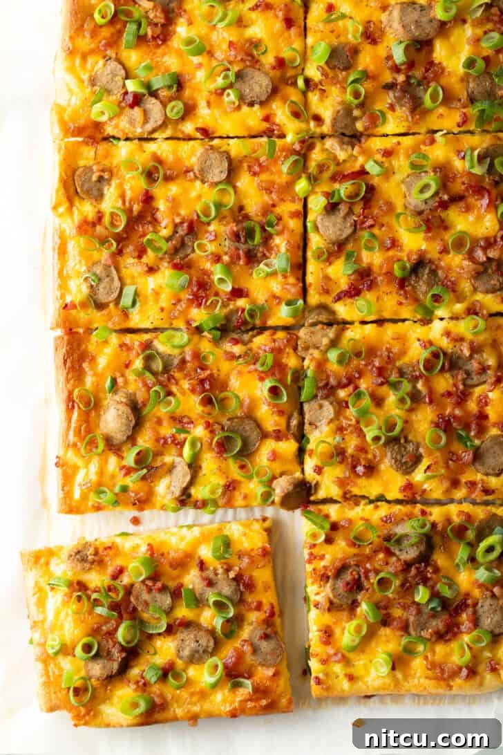 Daybreak Pizza 4 Another perspective of the rectangular baking sheet tray featuring the finished breakfast pizza, richly adorned with melted cheese, savory sausage, and fresh green onions. The pizza has been meticulously cut into 8 rectangular portions, with one slice slightly separated to highlight its perfect crust and enticing toppings.