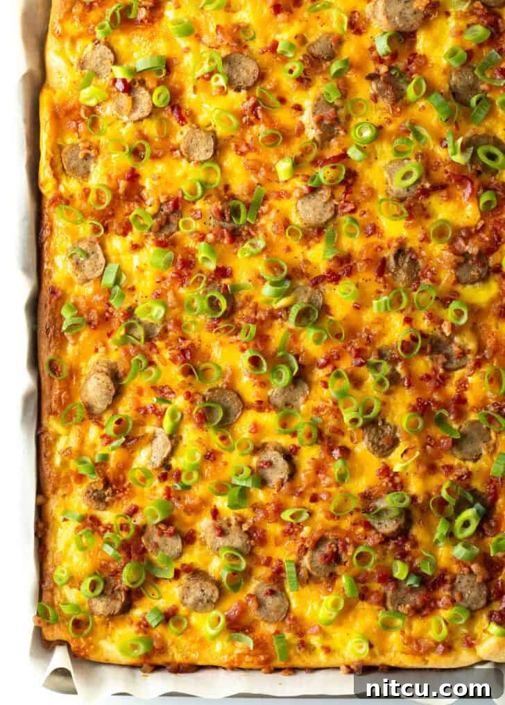 Daybreak Pizza 10 A complete view of the rectangle baking sheet tray, displaying the gloriously baked breakfast pizza, generously adorned with golden-brown cheeses and perfectly cooked sausage slices, ready to be garnished.