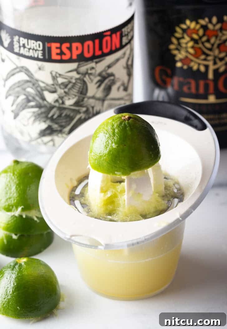 The Ultimate Frozen Margarita 5 Juicing a lime over a measuring glass.