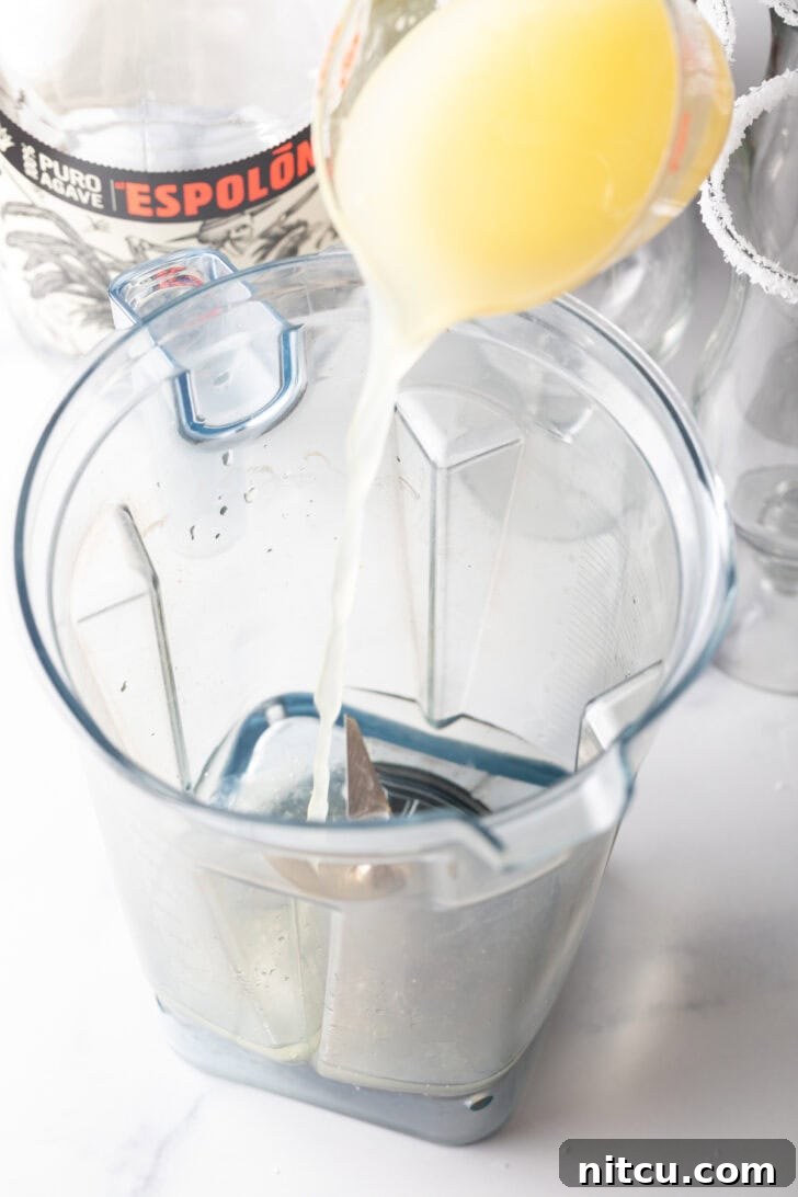 The Ultimate Frozen Margarita 6 Pouring citrus juice into a blender jar.