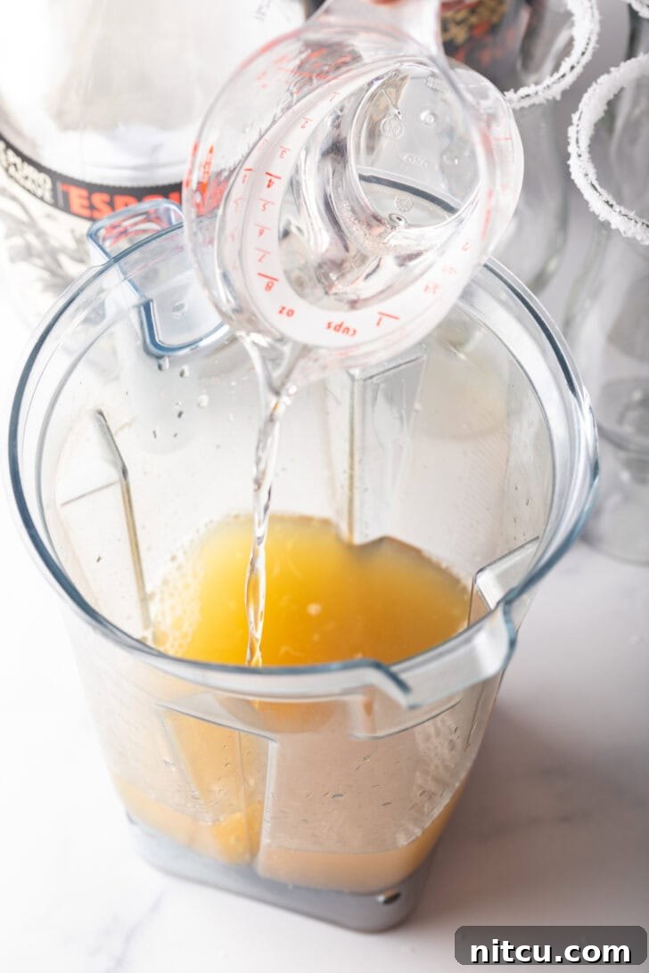 The Ultimate Frozen Margarita 7 Adding clear alcohol to a blender pitcher.