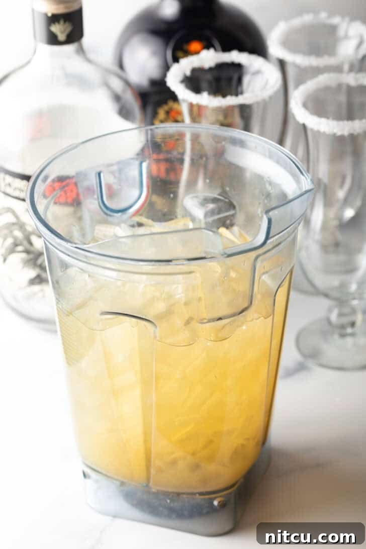 The Ultimate Frozen Margarita 8 Blender jar with citrus juice and alcohol.