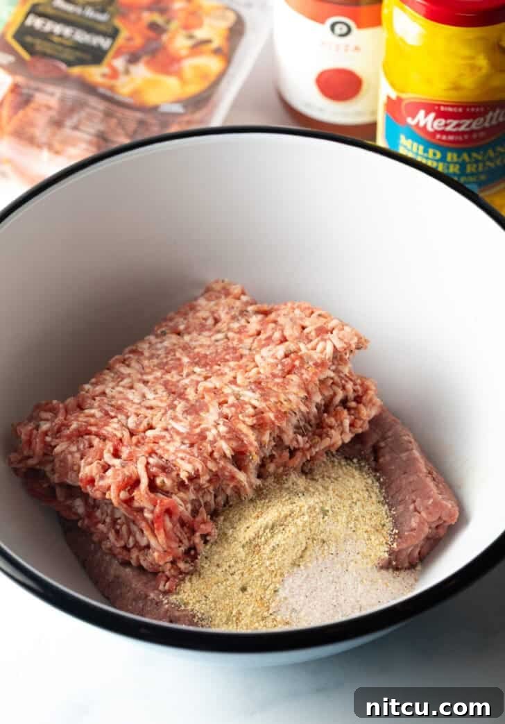 A white bowl containing the foundational ingredients for the pizza burger patties: ground beef, breadcrumbs, and seasonings, ready for mixing.