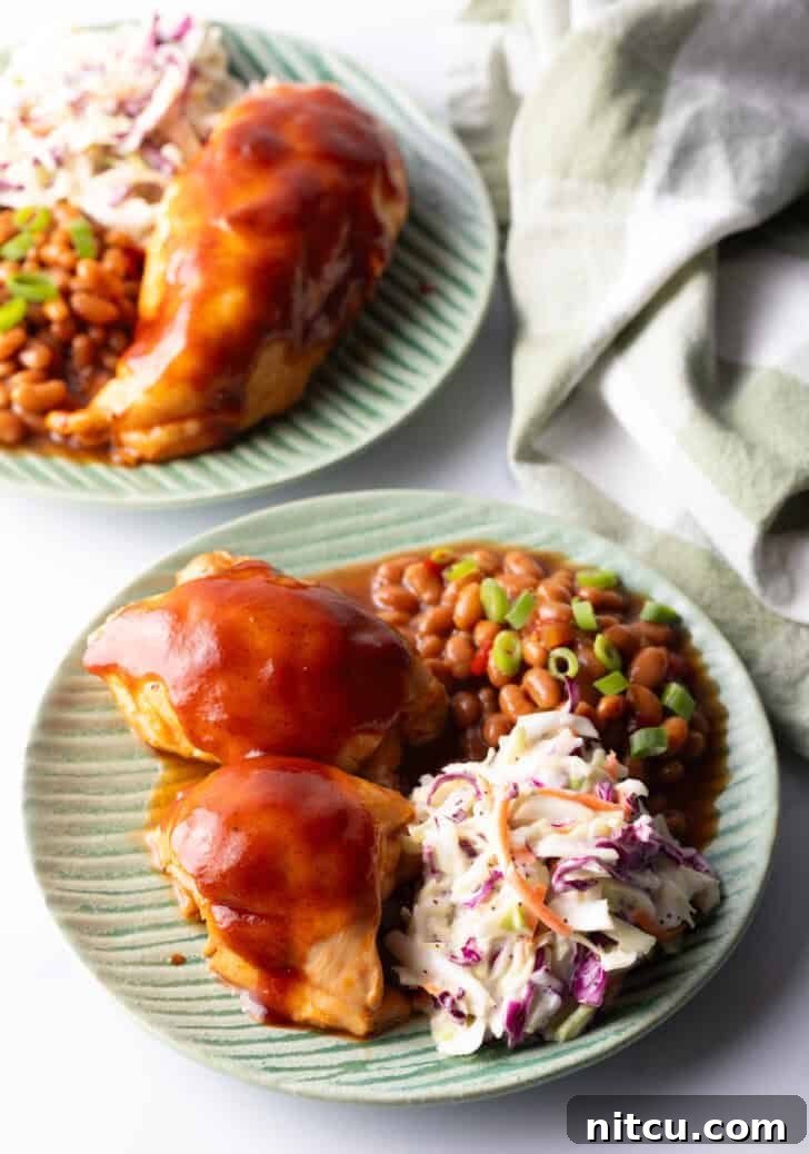 Green plate with BBQ chicken, coleslaw, and baked beans.