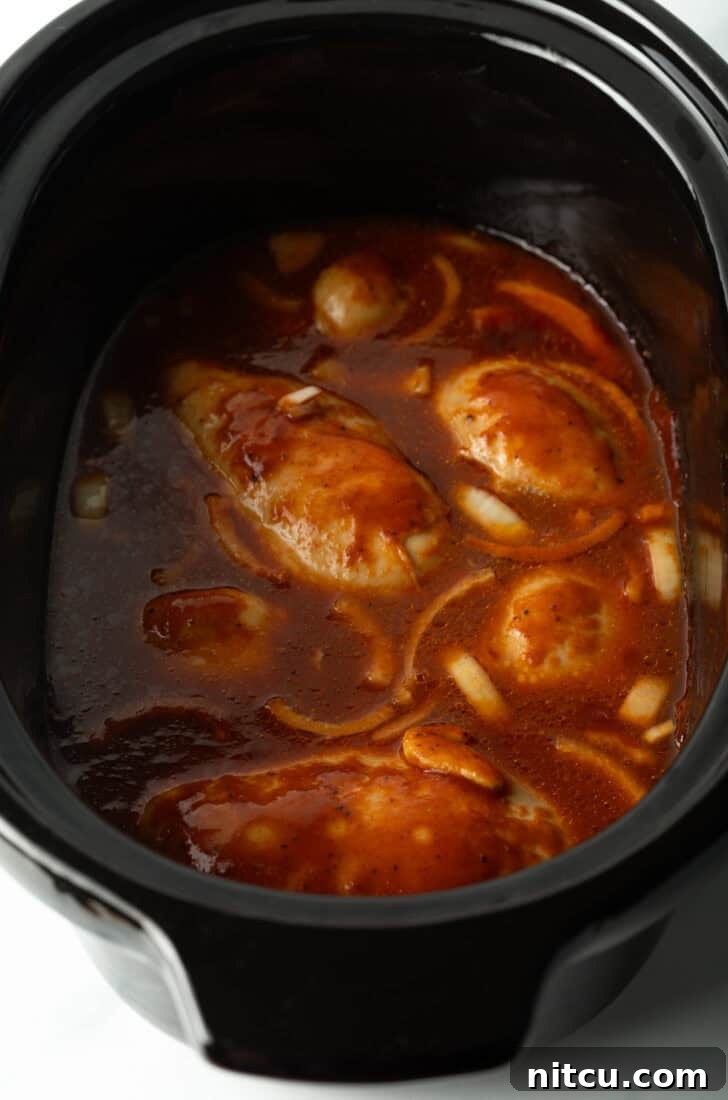 Crockpot with chicken thighs and barbecue sauce.