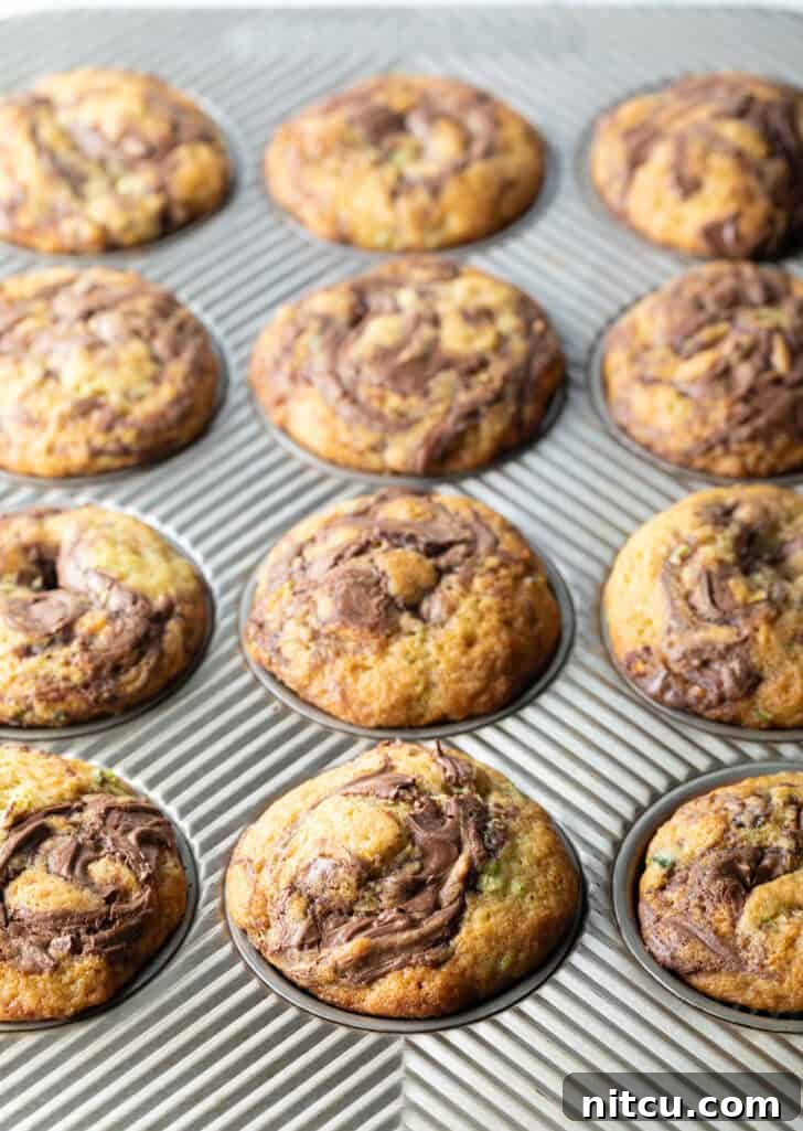 Decadent Zucchini Nutella Muffins 11 A dozen perfectly baked zucchini and Nutella swirl muffins, golden brown and enticing, still warm in their baking tin.
