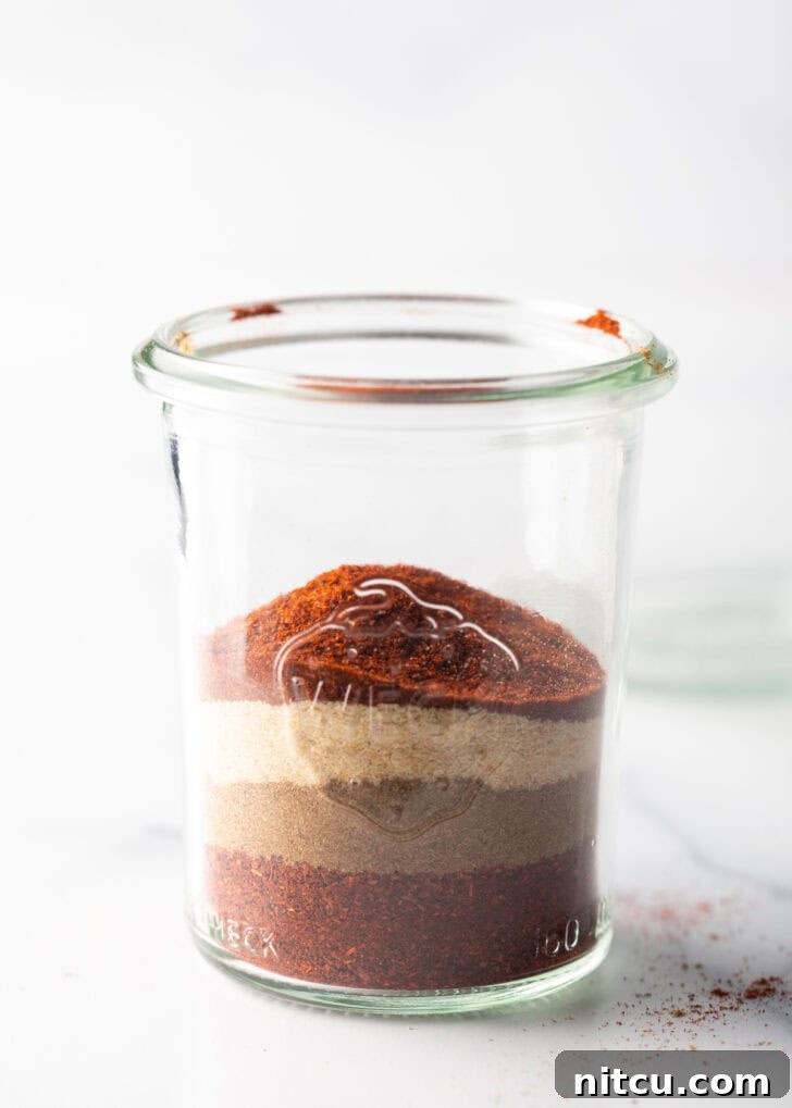 Zesty Chicken Taco Blend 5 Individual layers of distinct spices visible in a clear glass jar, before mixing.