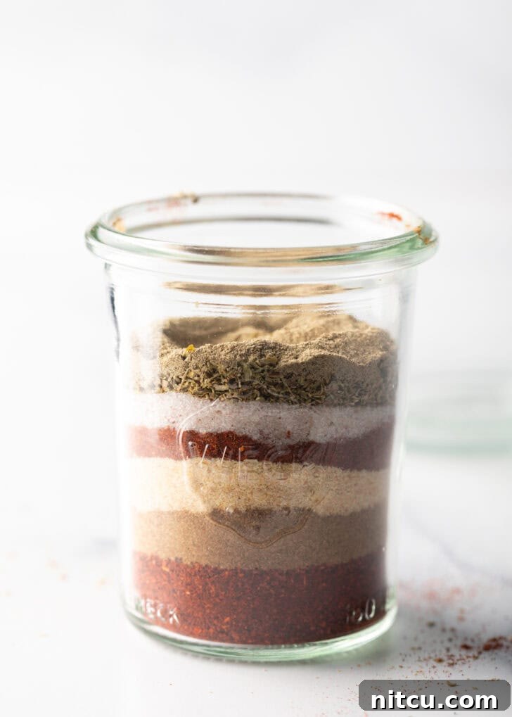 Zesty Chicken Taco Blend 6 A close-up view of vibrant spice layers settled at the bottom of a tall glass jar.