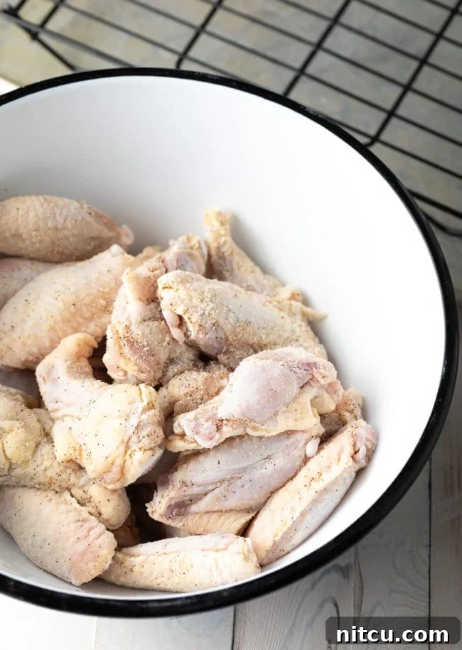 Raw chicken wings in a white mixing bowl.