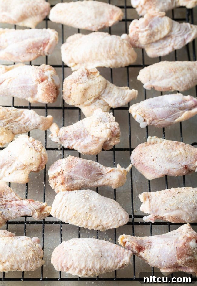Raw chicken wings and drummies on a wire rack.