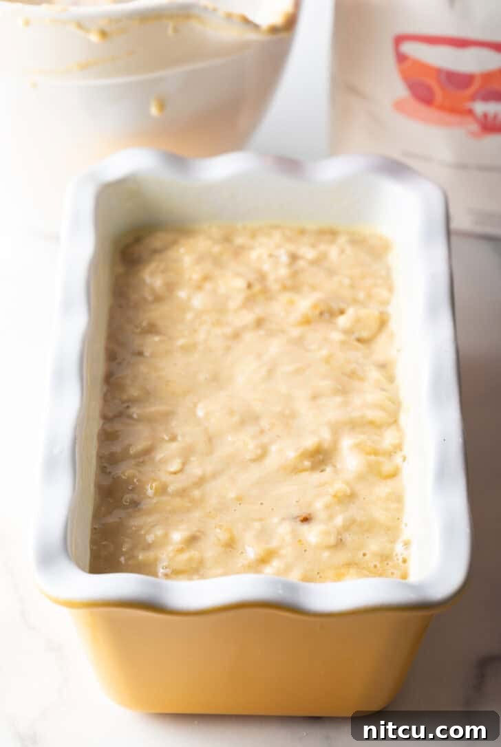 Effortless Banana Bread 10 Smooth banana bread batter poured into a clean white loaf pan, ready for baking.