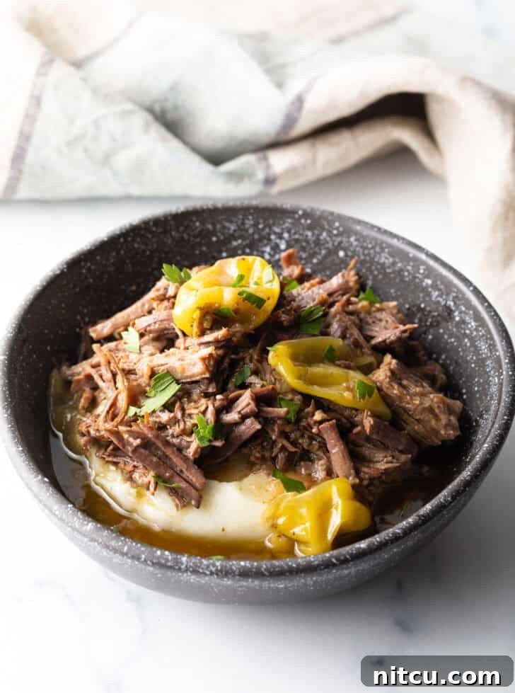 Melt-in-Your-Mouth Mississippi Pot Roast 13 Black bowl with a layer of mashed potatoes topped with shredded pot roast and pepperoncinis.