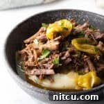Melt-in-Your-Mouth Mississippi Pot Roast 14 Black bowl with a layer of mashed potatoes topped with shredded pot roast and pepperoncinis.