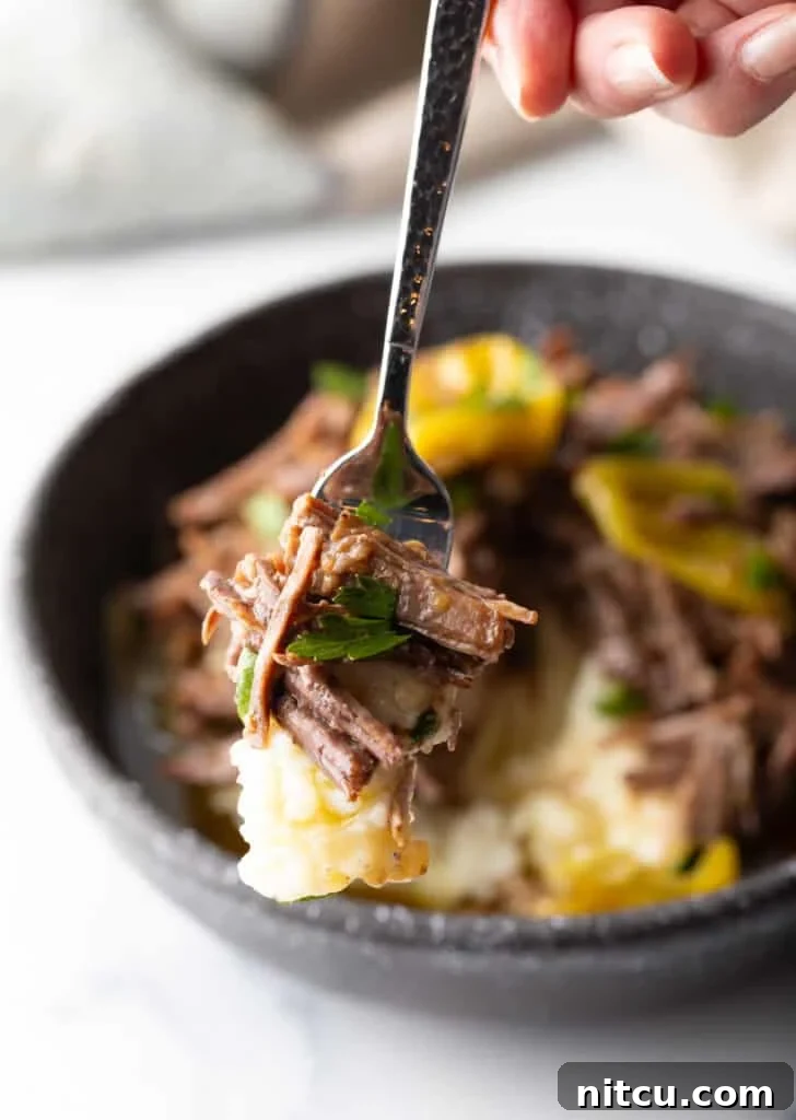 Melt-in-Your-Mouth Mississippi Pot Roast 15 Hand holding a forkful of pot roast to camera.