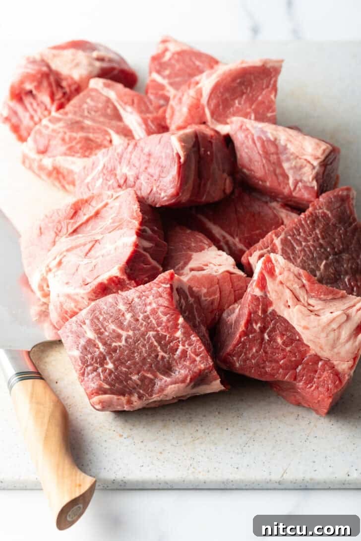 Melt-in-Your-Mouth Mississippi Pot Roast 7 Chunks of raw meat on a cutting board with sharp knife.