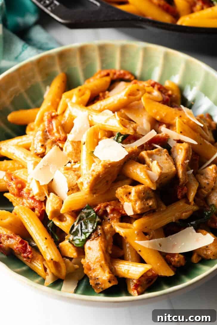Proposal-Worthy Chicken Pasta 5 A vibrant green bowl filled with spicy Marry Me Chicken Pasta, garnished with fresh basil leaves.