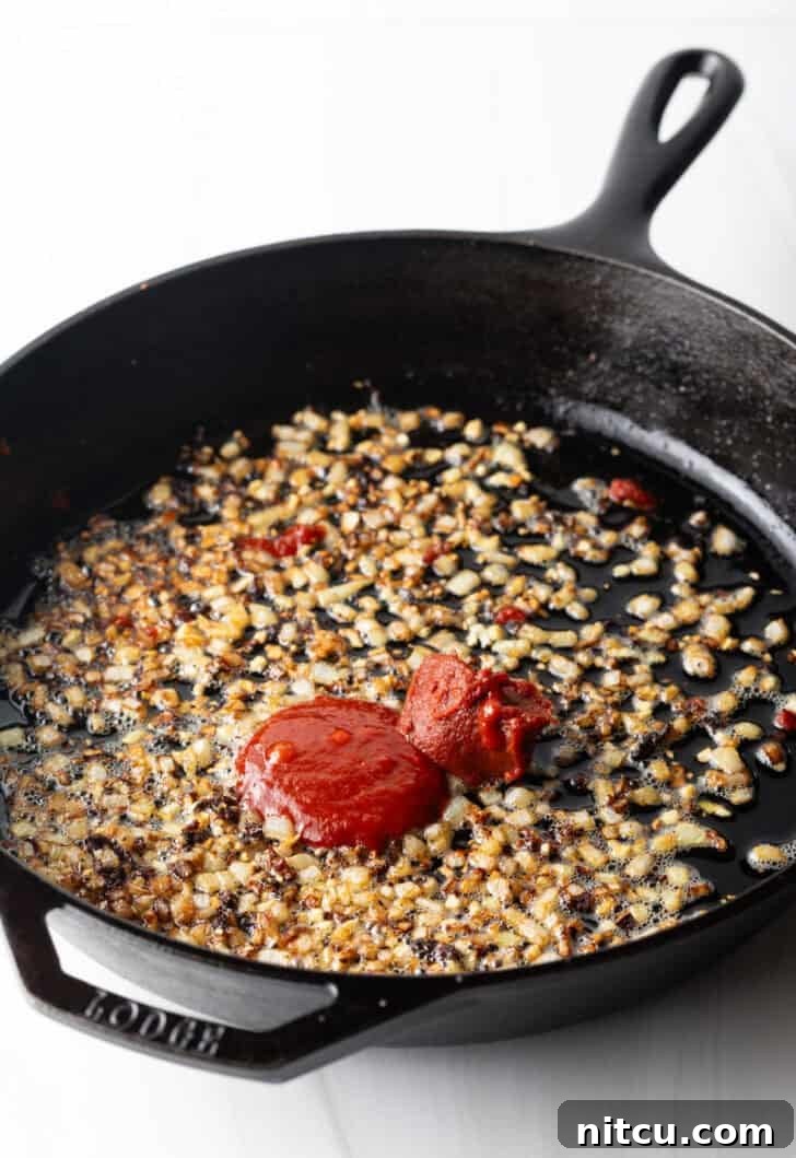 Proposal-Worthy Chicken Pasta 7 Sautéing minced garlic and rich tomato paste in a cast iron skillet, building the flavor base.