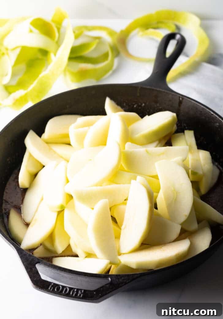 Caramelized Apple Bliss 9 A mounded pile of raw apple slices in a cast iron skillet, ready to be fried.