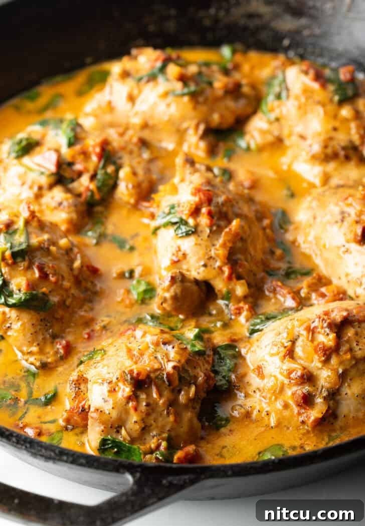 Creamy Tuscan chicken thighs in a skillet, ready to serve.