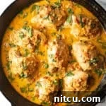 Top down view cast iron skillet packed with chicken thighs in a creamy Tuscan cream sauce.