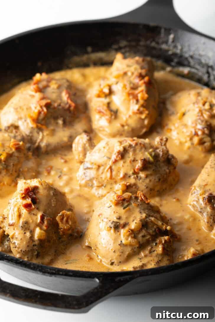 Cooked chicken thighs in cream sauce in a cast iron skillet.
