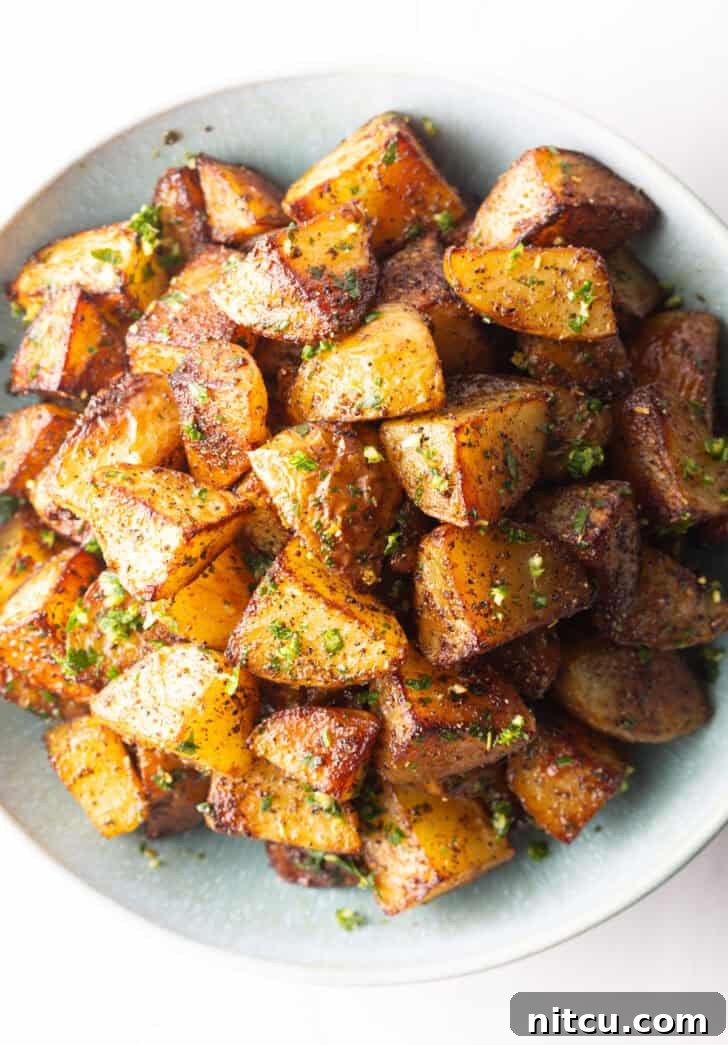 Crispy Potato Gold 11 Top down view of a white bowl brimming with pieces of golden crispy Yukon potatoes.