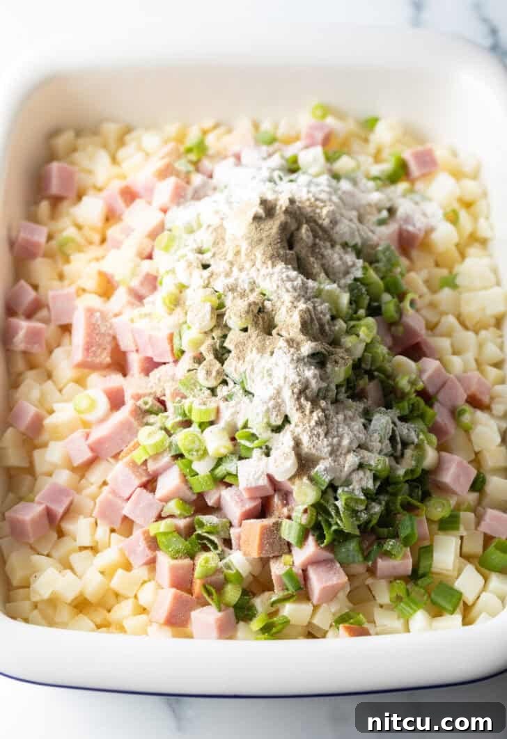 Golden Ham and Potato Bake 7 Mixing potatoes, ham, green onions, and garlic in a baking dish.